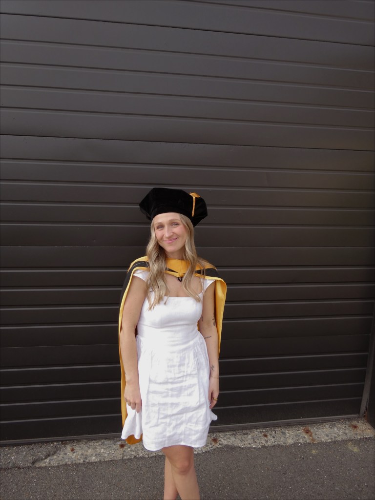 Cara, in white dress and graduation regalia.